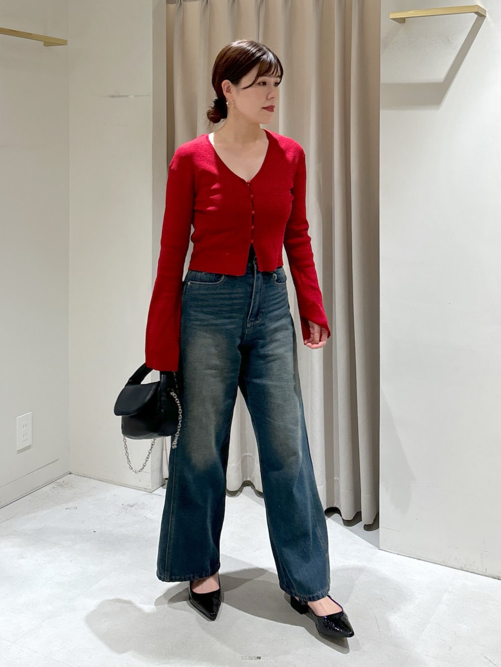 レッド系のニット/セーター、ブルー系のデニムパンツ、ブラック系のショルダーバッグを着用したレディースの秋コーディネートの2枚目の写真