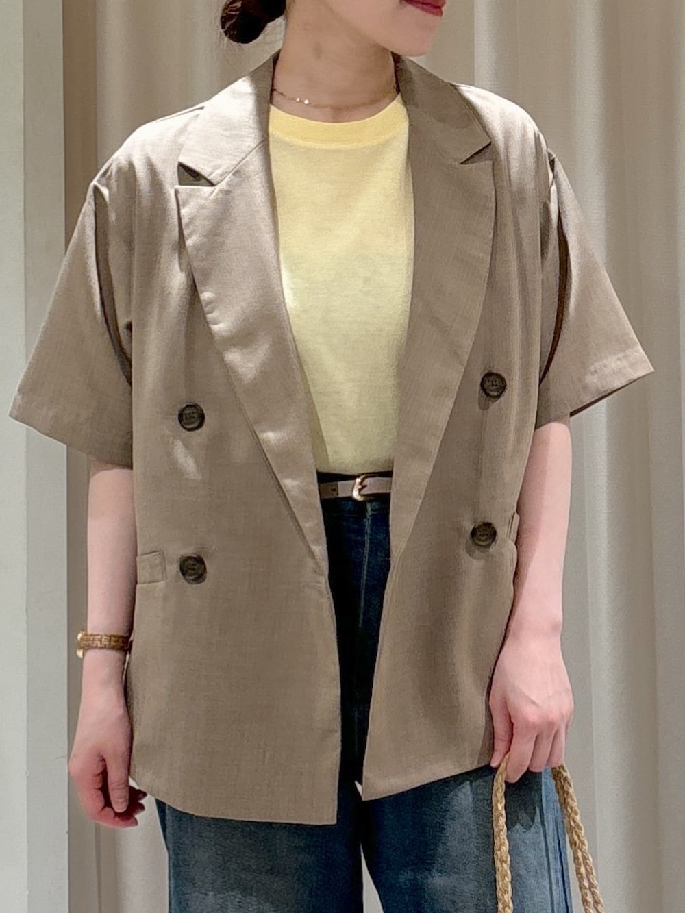 ブラウン系のテーラードジャケット、イエロー系のTシャツ/カットソー、ブルー系のデニムパンツを着用したレディースの春コーディネートの2枚目の写真