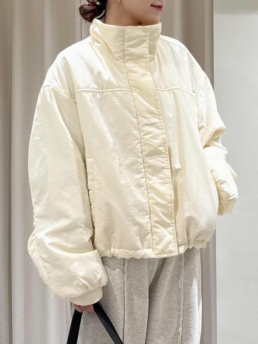 ホワイト系のブルゾン、ブラック系のハンドバッグ、ホワイト系のスウェットパンツを着用したレディースの秋コーディネートの3枚目の写真