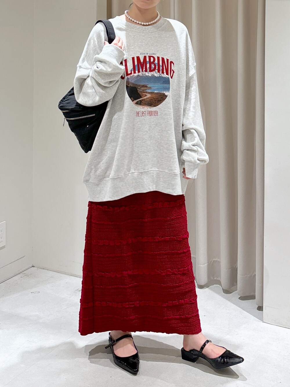 ホワイト系のスウェット、レッド系のスカート、ブラック系のパンプスを着用したレディースの秋コーディネートの3枚目の写真