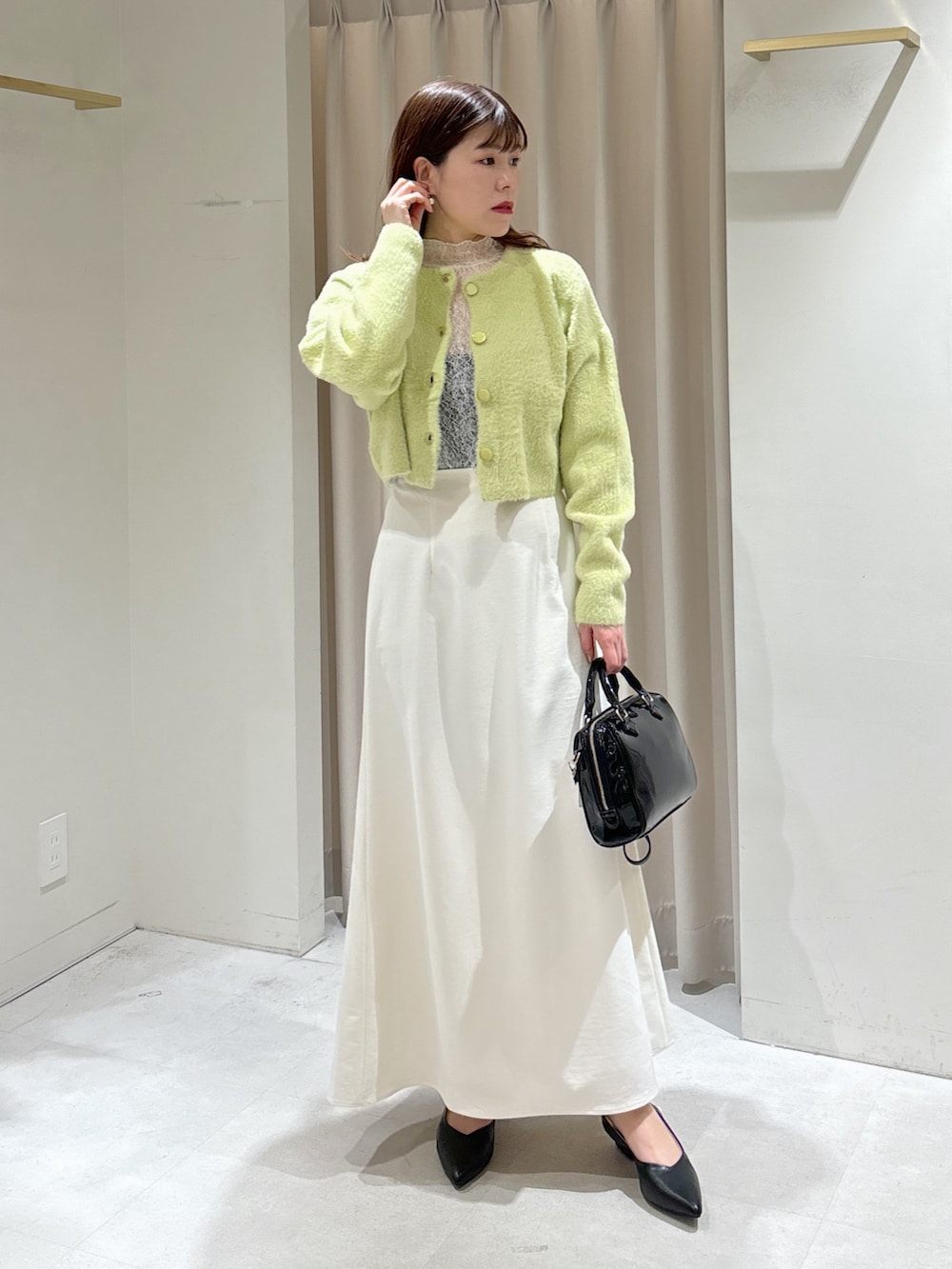 グリーン系のカーディガン/ボレロ、ホワイト系のTシャツ/カットソー、ホワイト系のスカートを着用したレディースの冬コーディネートの7枚目の写真