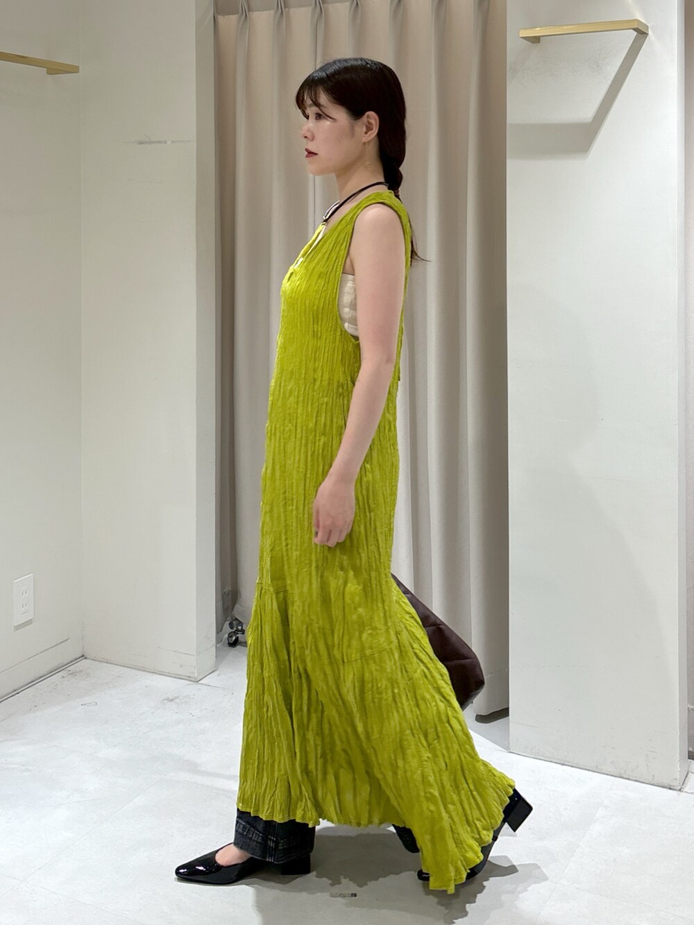 グリーン系のワンピース、ブラウン系のトートバッグ、ブラック系のデニムパンツを着用したレディースの秋コーディネートの4枚目の写真