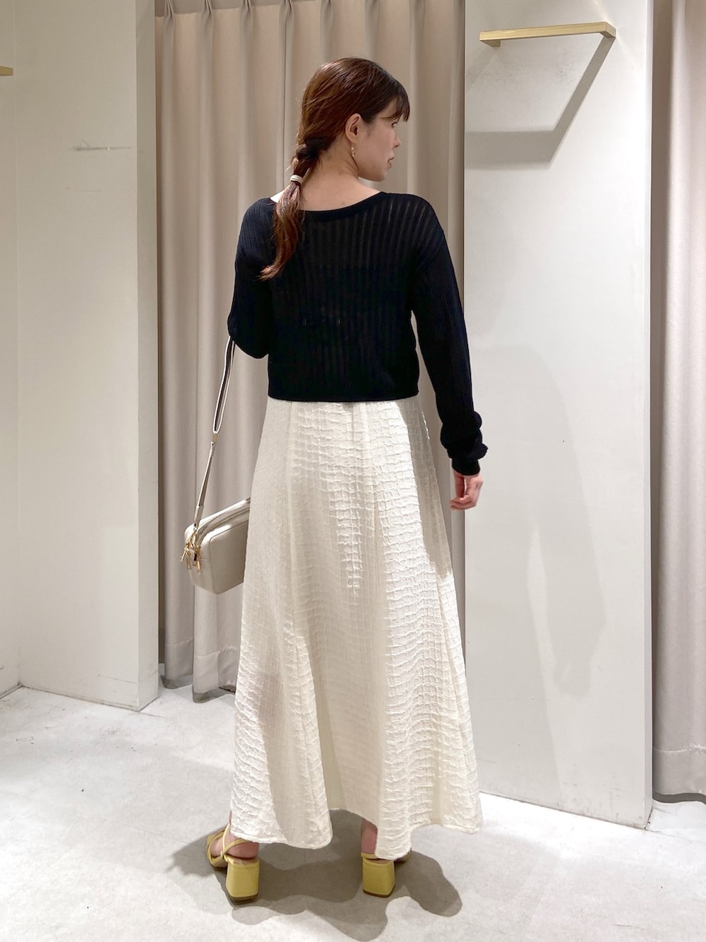 ホワイト系のワンピース、ブラック系のカーディガン/ボレロ、ホワイト系のボディバッグ/ウエストポーチを着用したレディースの春コーディネートの4枚目の写真