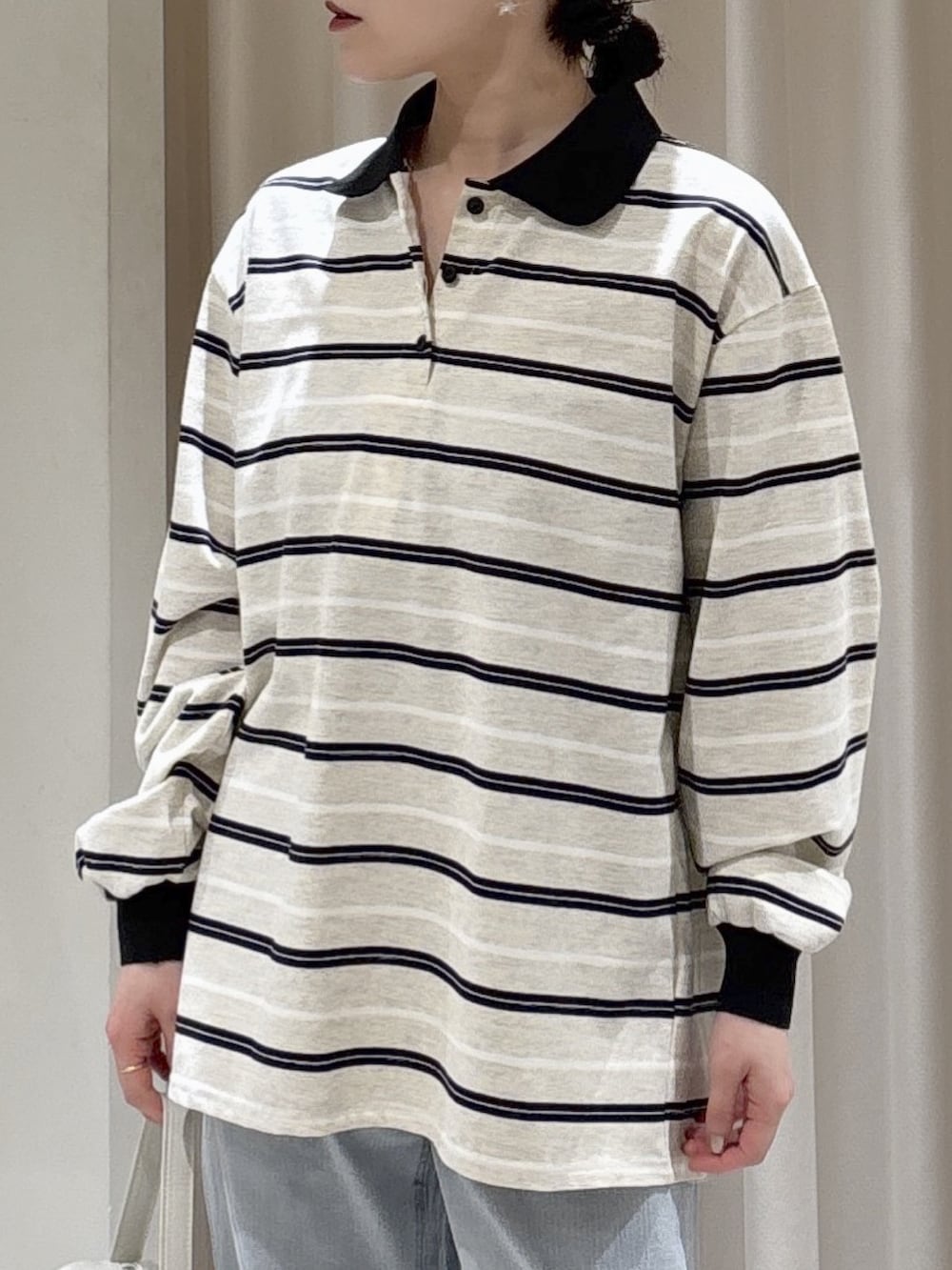 グレー系のTシャツ/カットソー、ホワイト系のハンドバッグ、ブルー系のデニムパンツを着用したレディースの春コーディネートの3枚目の写真