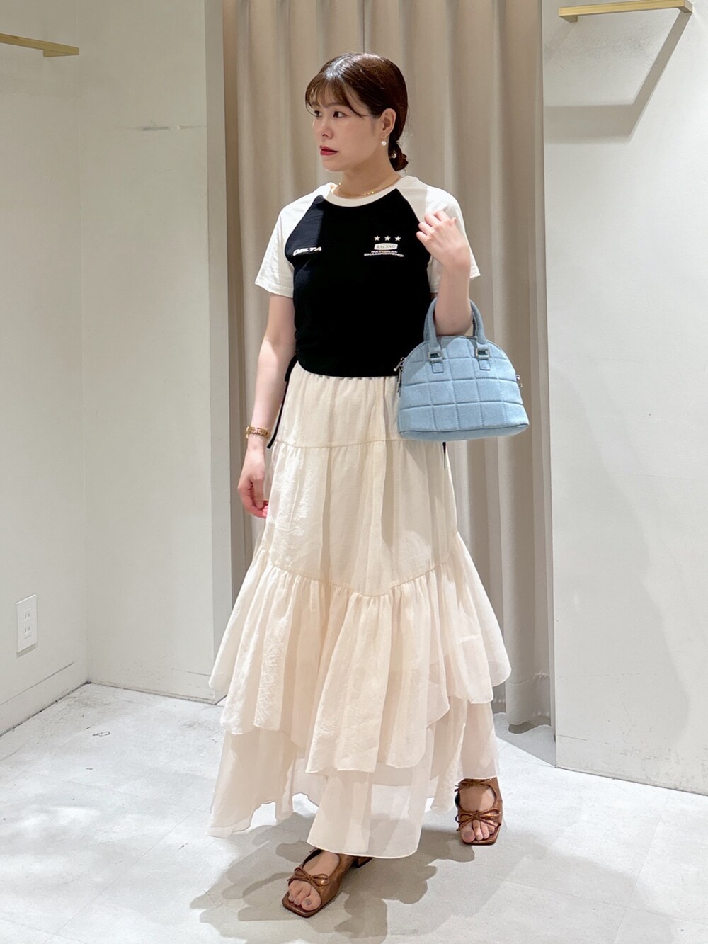 ブラック系のTシャツ/カットソー、ブルー系のトートバッグ、ホワイト系のスカートを着用したレディースの夏コーディネートの2枚目の写真