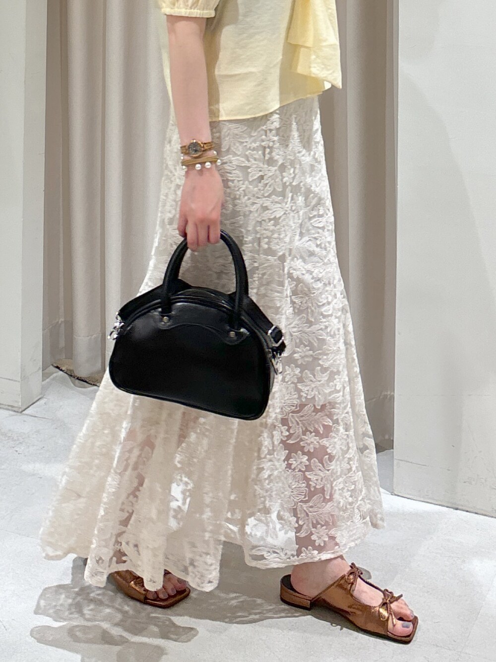 イエロー系のシャツ/ブラウス、ブラック系のトートバッグ、ホワイト系のスカートを着用したレディースの夏コーディネートの3枚目の写真