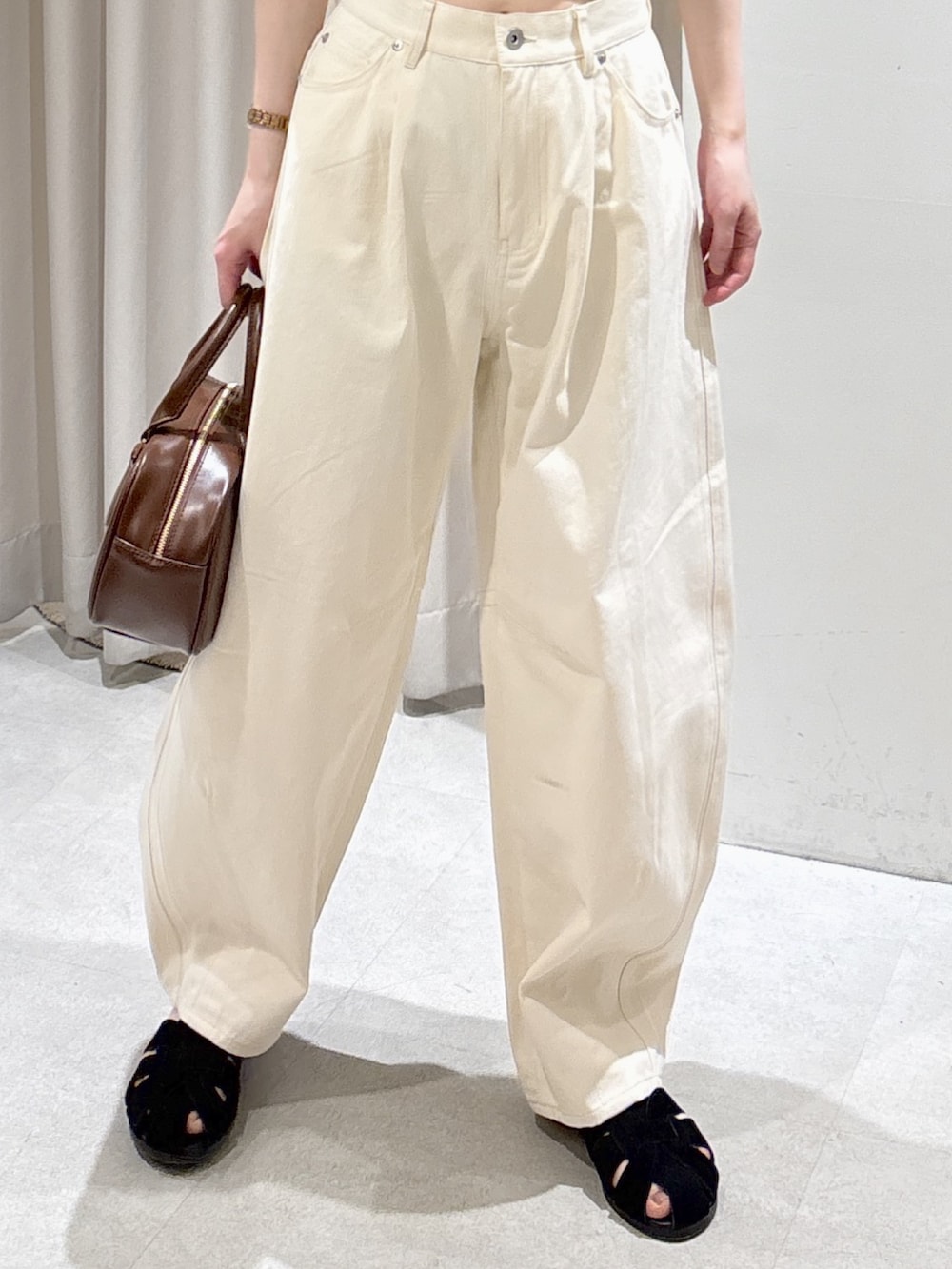 イエロー系のニット/セーター、ホワイト系のその他パンツ、ブラウン系のハンドバッグを着用したレディースの春コーディネートの5枚目の写真