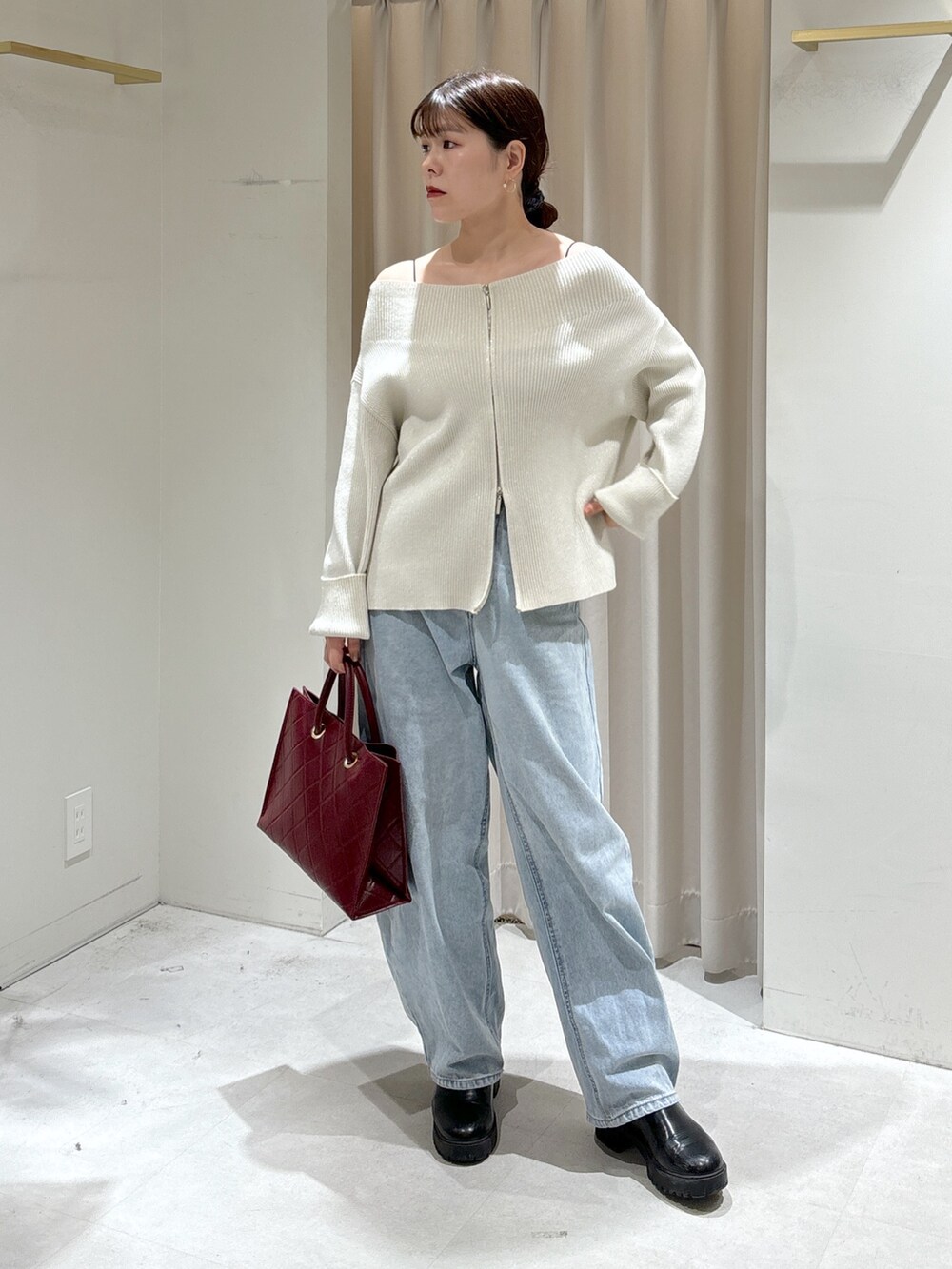ホワイト系のニット/セーター、レッド系のショルダーバッグ、ブルー系のデニムパンツを着用したレディースの冬コーディネートの2枚目の写真