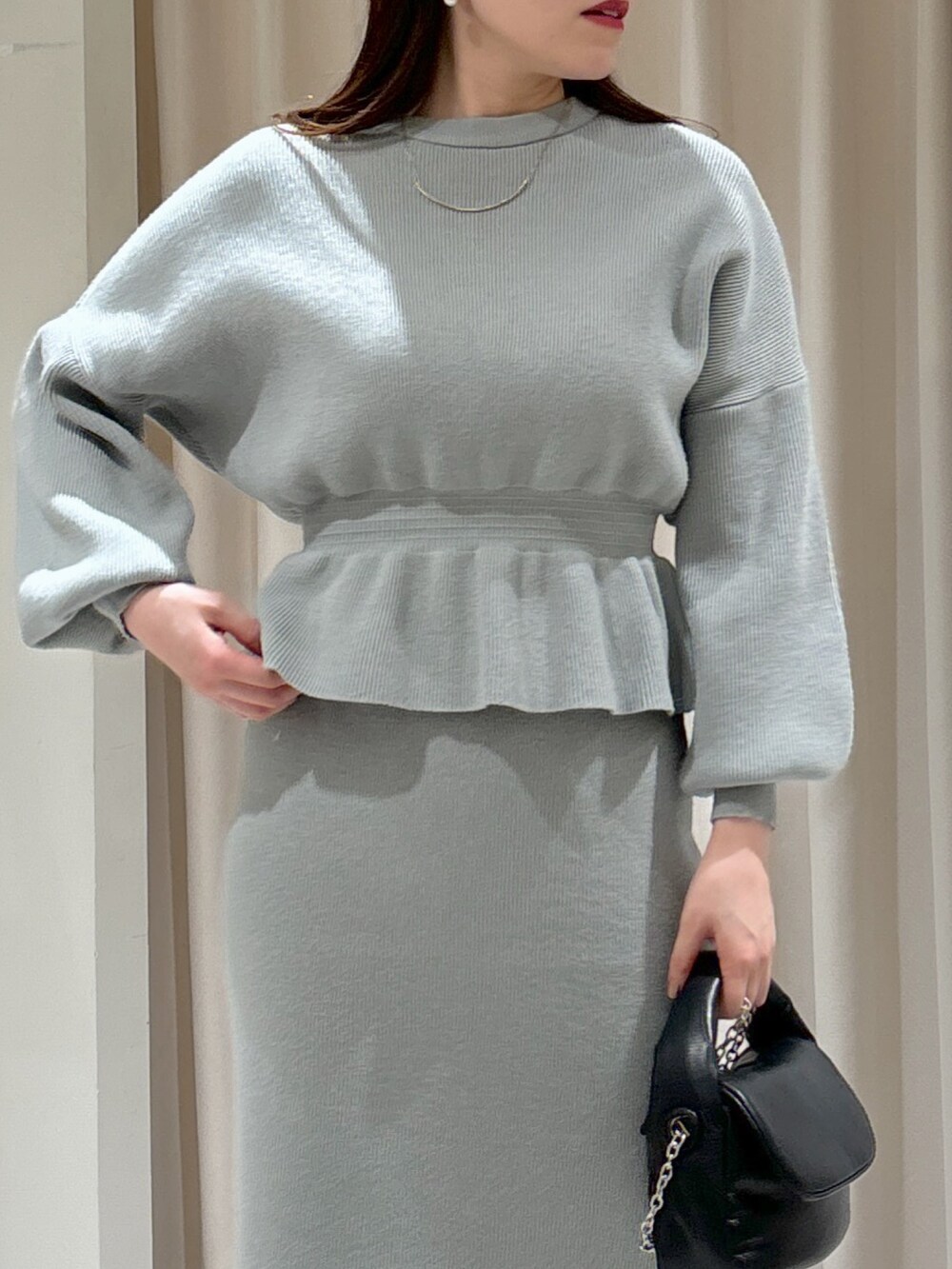 グリーン系のワンピース、ブラック系のショルダーバッグ、グレー系のブーツを着用したレディースの冬コーディネートの3枚目の写真