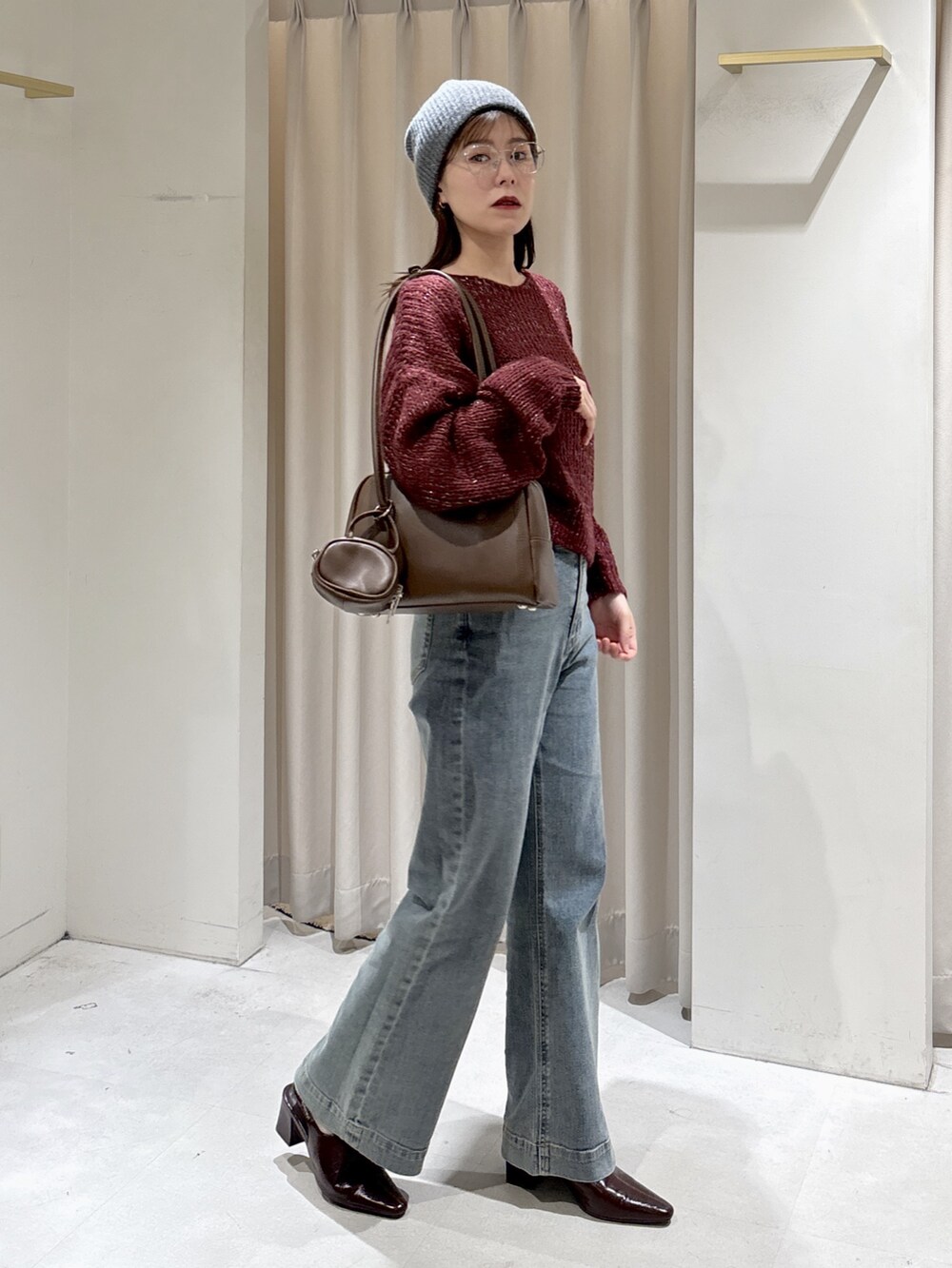 レッド系のニット/セーター、ブラウン系のトートバッグ、ブルー系のデニムパンツを着用したレディースの秋コーディネートの7枚目の写真