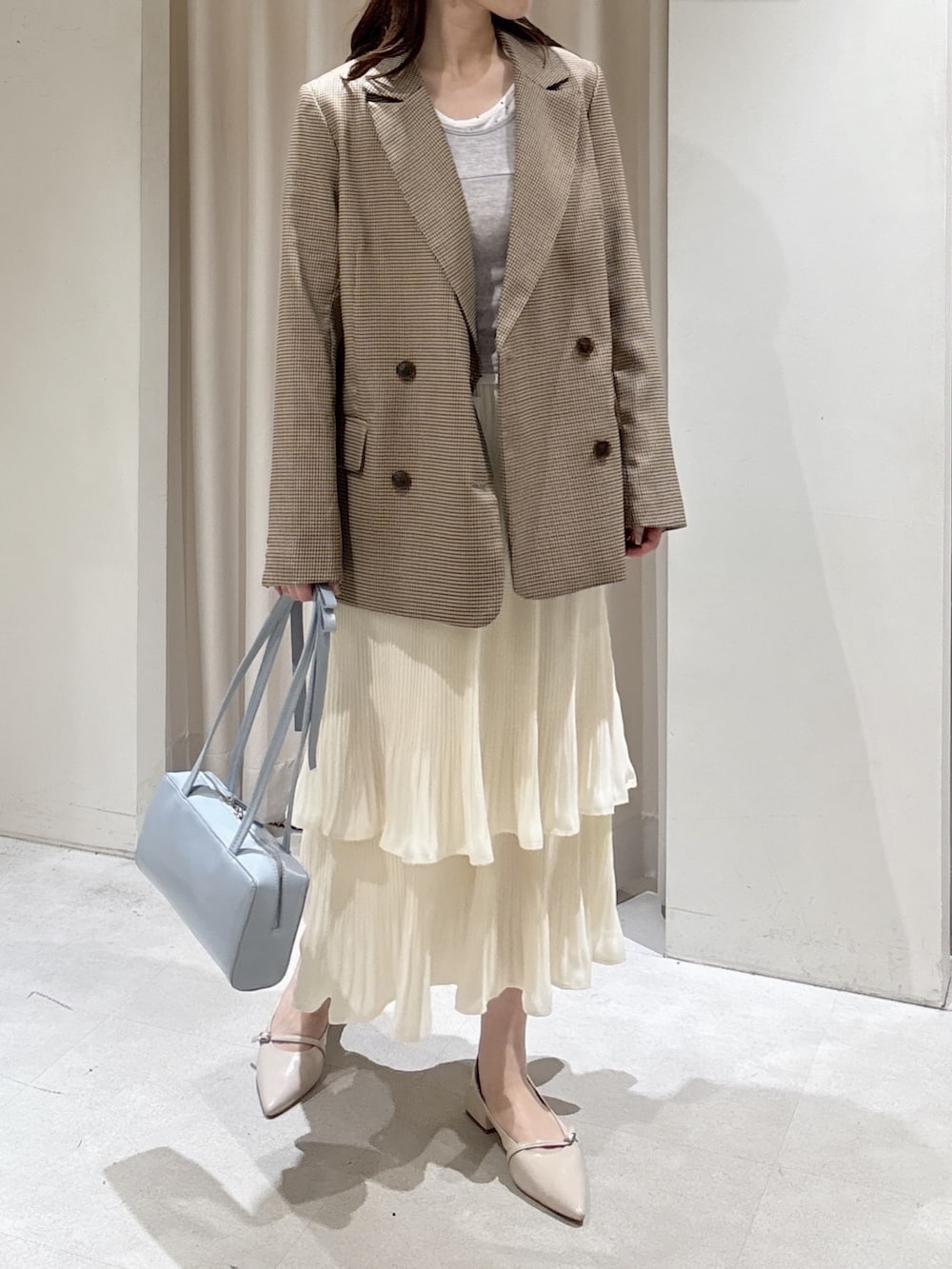 ベージュ系のテーラードジャケット、グレー系のTシャツ/カットソー、ホワイト系のスカートを着用したレディースの春コーディネートの2枚目の写真