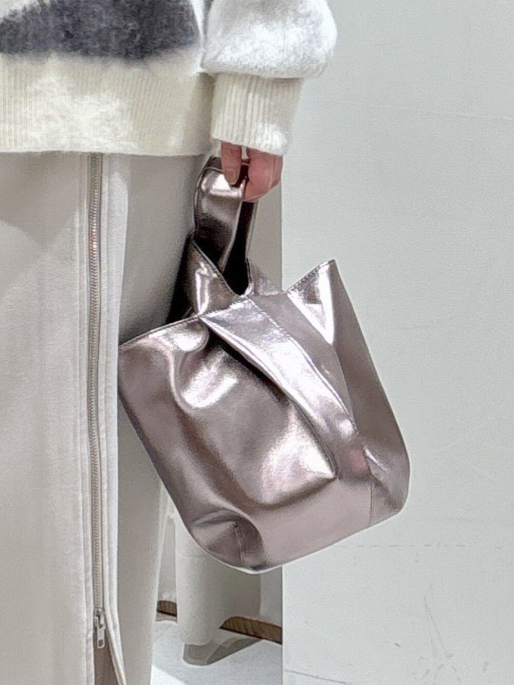 ホワイト系のニット/セーター、グレー系のスカート、シルバー系のハンドバッグを着用したレディースの冬コーディネートの7枚目の写真