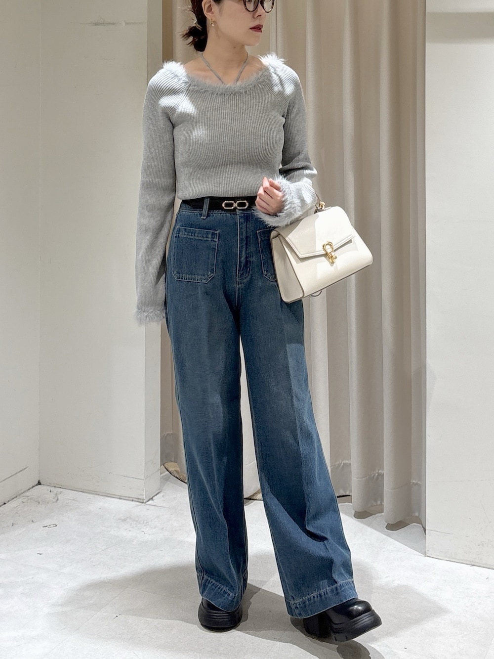 グレー系のニット/セーター、ブルー系のデニムパンツ、ホワイト系のトートバッグを着用したレディースの秋コーディネートの2枚目の写真