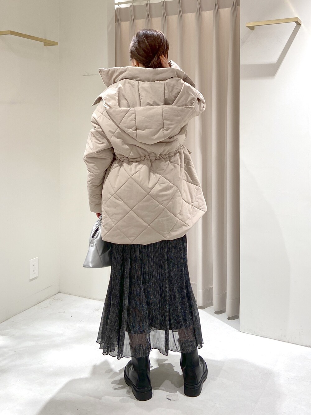 ベージュ系のダウンジャケット/コート、ブラック系のスカート、シルバー系のショルダーバッグを着用したレディースの秋コーディネートの3枚目の写真