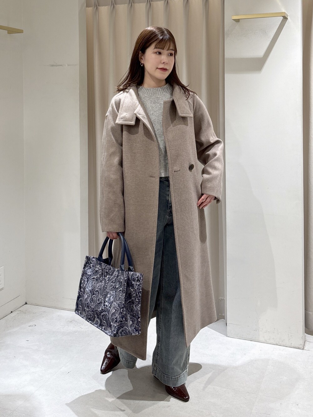ブラウン系のステンカラーコート、ブルー系のトートバッグ、ブルー系のデニムパンツを着用したレディースの秋コーディネートの4枚目の写真