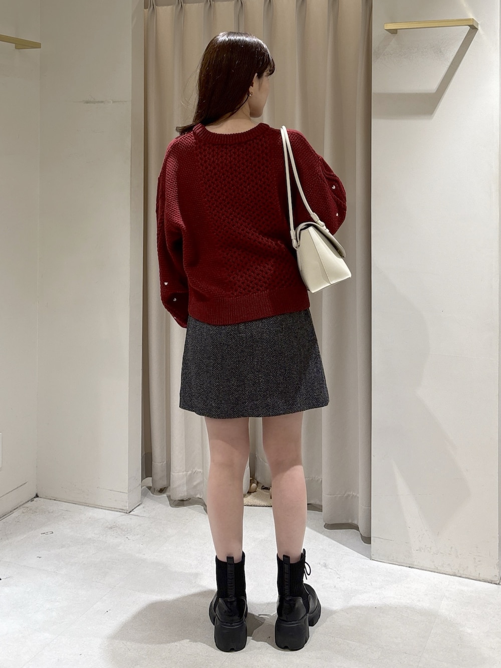 レッド系のニット/セーター、ホワイト系のショルダーバッグ、ブラック系のスカートを着用したレディースの冬コーディネートの4枚目の写真
