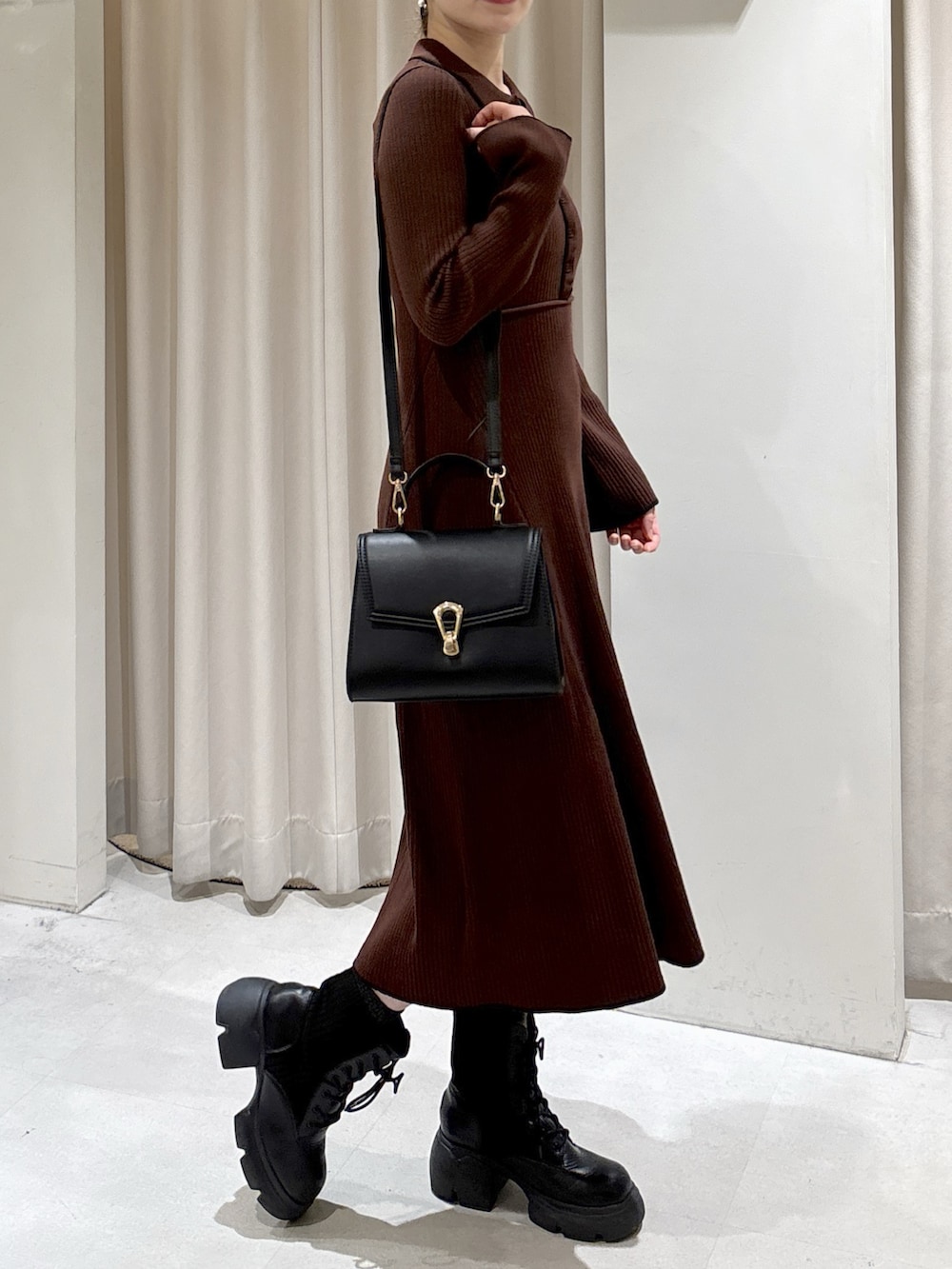 ブラウン系のワンピース、ブラック系のトートバッグ、ブラック系のブーツを着用したレディースの秋コーディネートの6枚目の写真