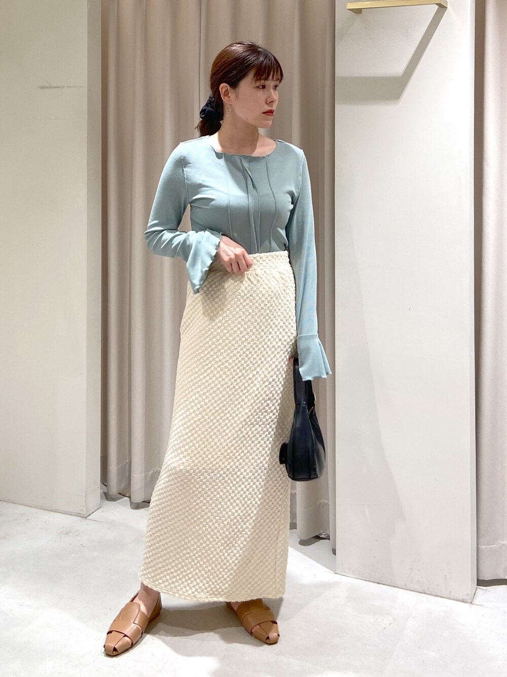 ホワイト系のトレンチコート、ブラック系のショルダーバッグ、ホワイト系のスカートを着用したレディースの春コーディネートの5枚目の写真