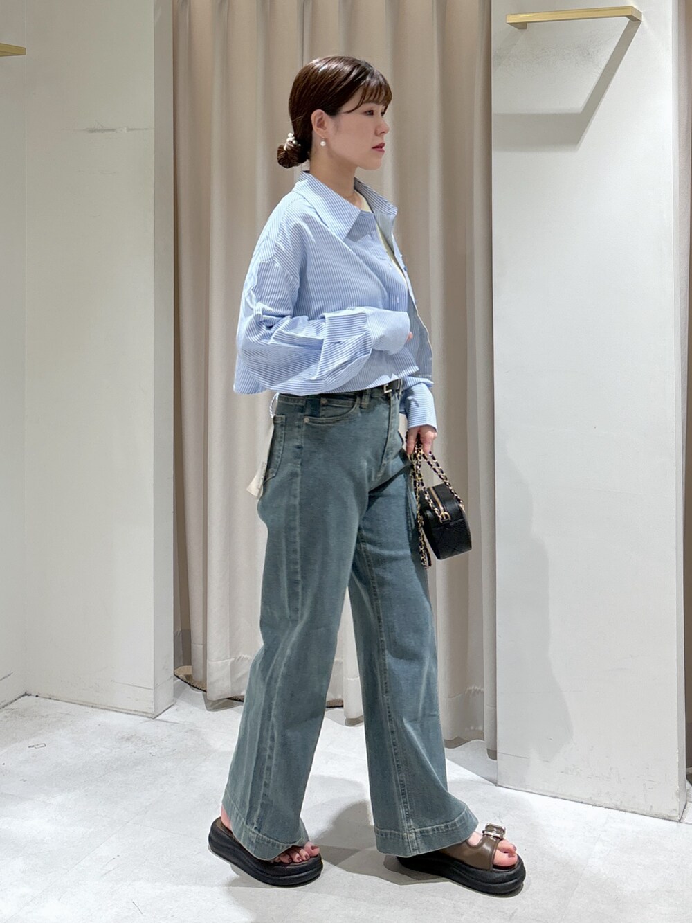 ブルー系のシャツ/ブラウス、イエロー系のタンクトップ、ブラック系のショルダーバッグを着用したレディースの夏コーディネートの4枚目の写真