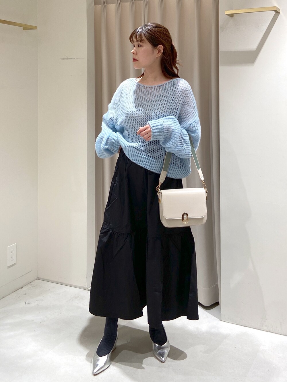 ブルー系のニット/セーター、ホワイト系のショルダーバッグ、ブラック系のスカートを着用したレディースの冬コーディネートの2枚目の写真