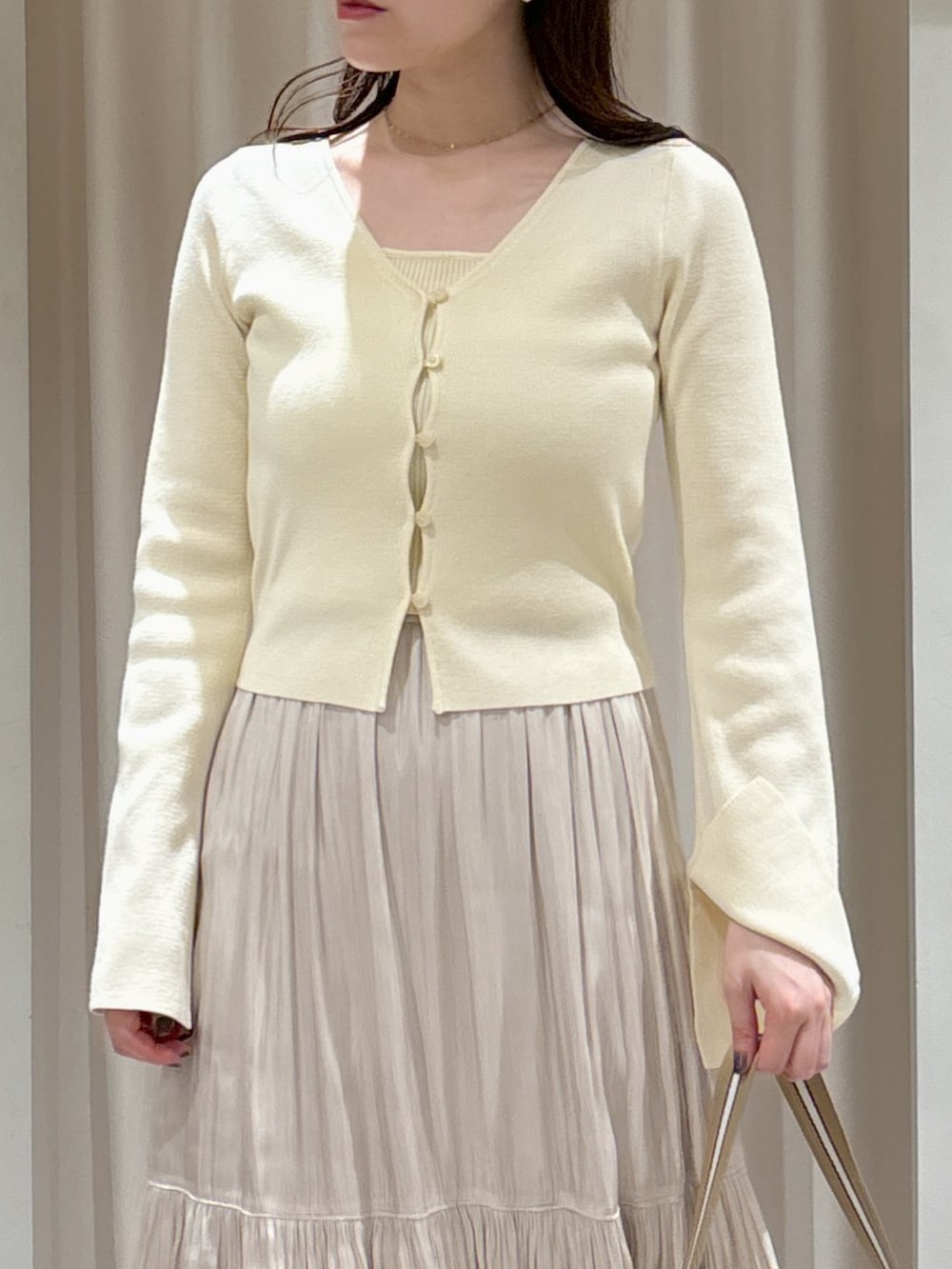 ホワイト系のニット/セーター、ベージュ系のショルダーバッグ、ホワイト系のスカートを着用したレディースの春コーディネートの2枚目の写真