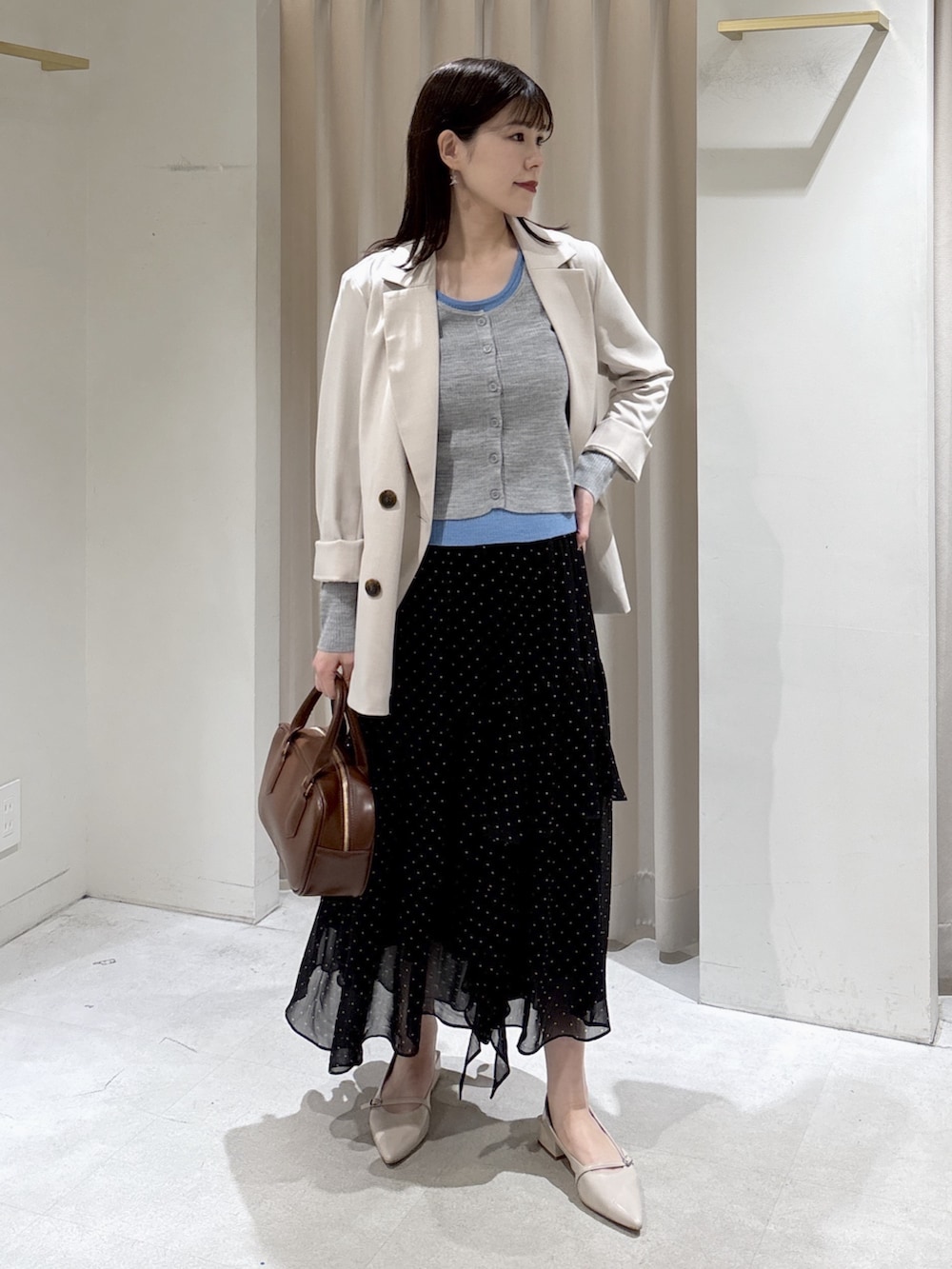 グレー系のニット/セーター、ブラック系のスカート、ブラウン系のハンドバッグを着用したレディースの春コーディネートの5枚目の写真