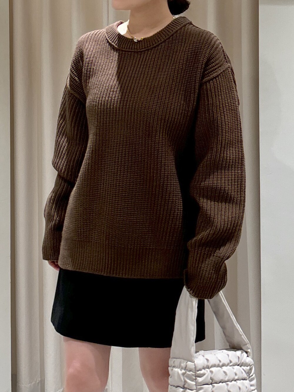 ブラウン系のニット/セーター、ホワイト系のハンドバッグ、ブラック系のスカートを着用したレディースの秋コーディネートの3枚目の写真