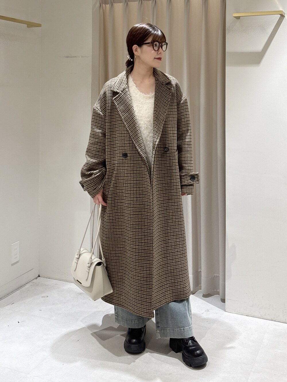 ホワイト系のニット/セーター、ブルー系のデニムパンツ、ホワイト系のショルダーバッグを着用したレディースの冬コーディネートの8枚目の写真