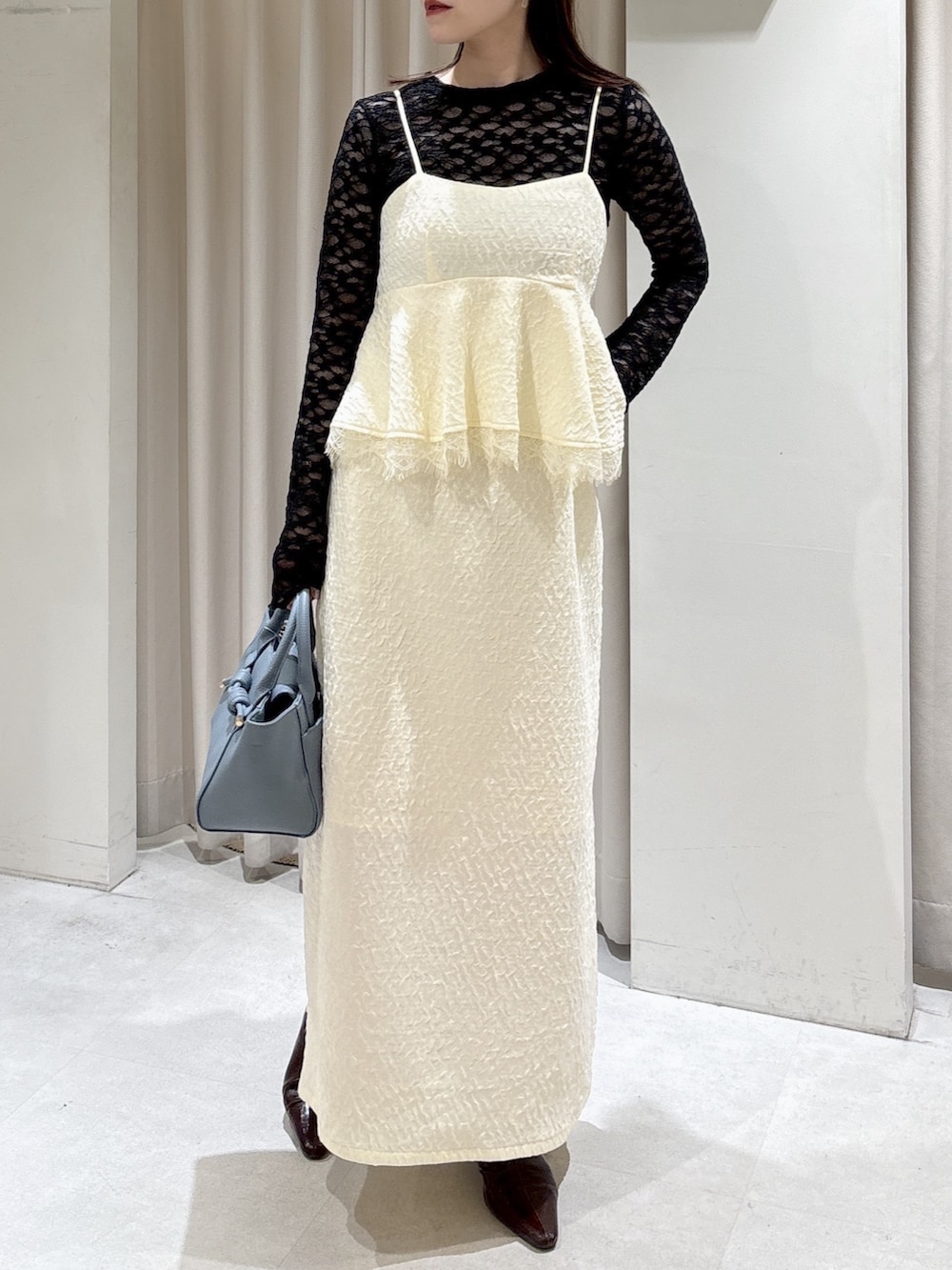 ホワイト系のワンピース、ブラック系のTシャツ/カットソー、ブルー系のハンドバッグを着用したレディースの冬コーディネートの2枚目の写真