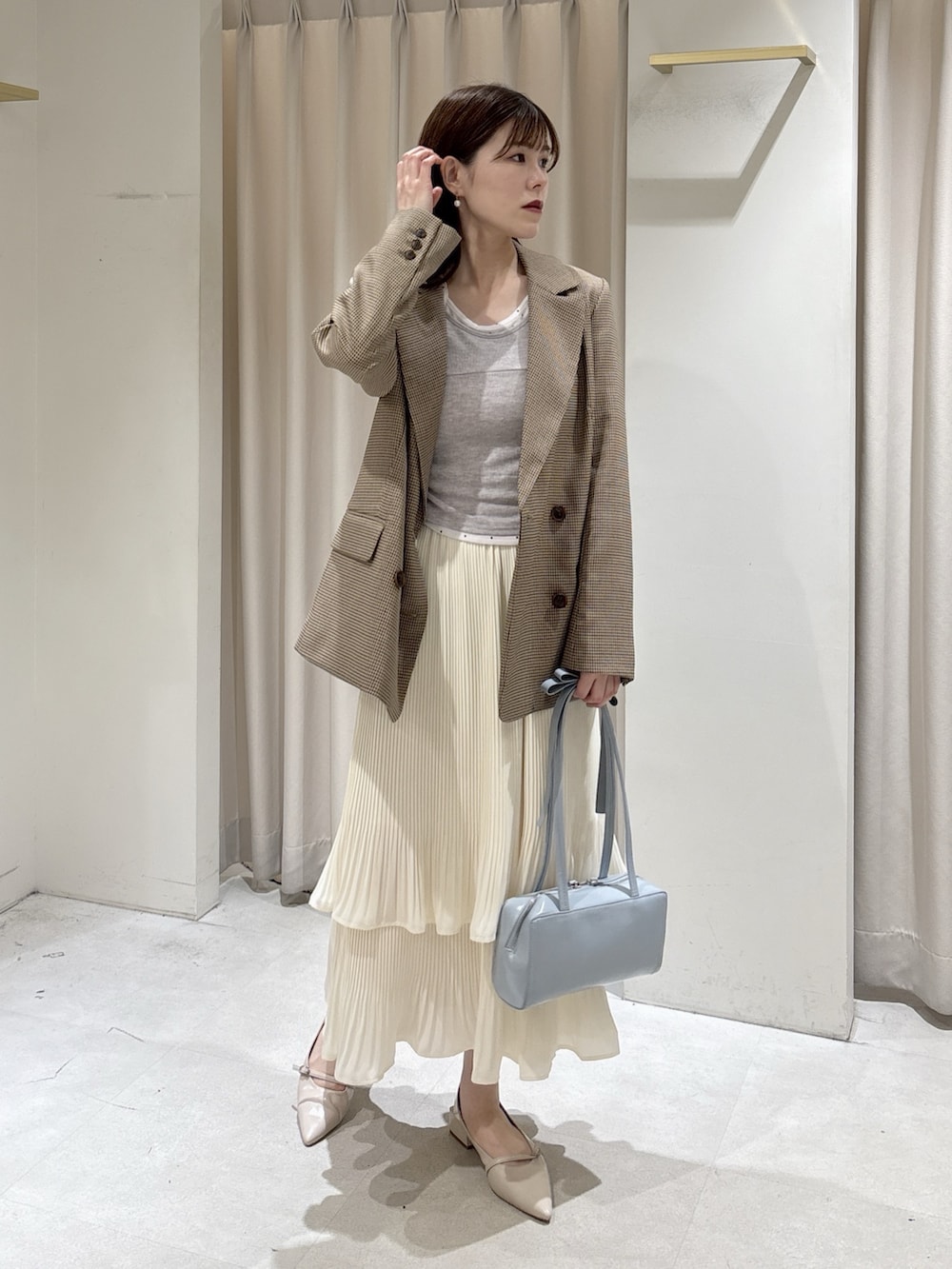 ベージュ系のテーラードジャケット、グレー系のTシャツ/カットソー、ホワイト系のスカートを着用したレディースの春コーディネートの4枚目の写真