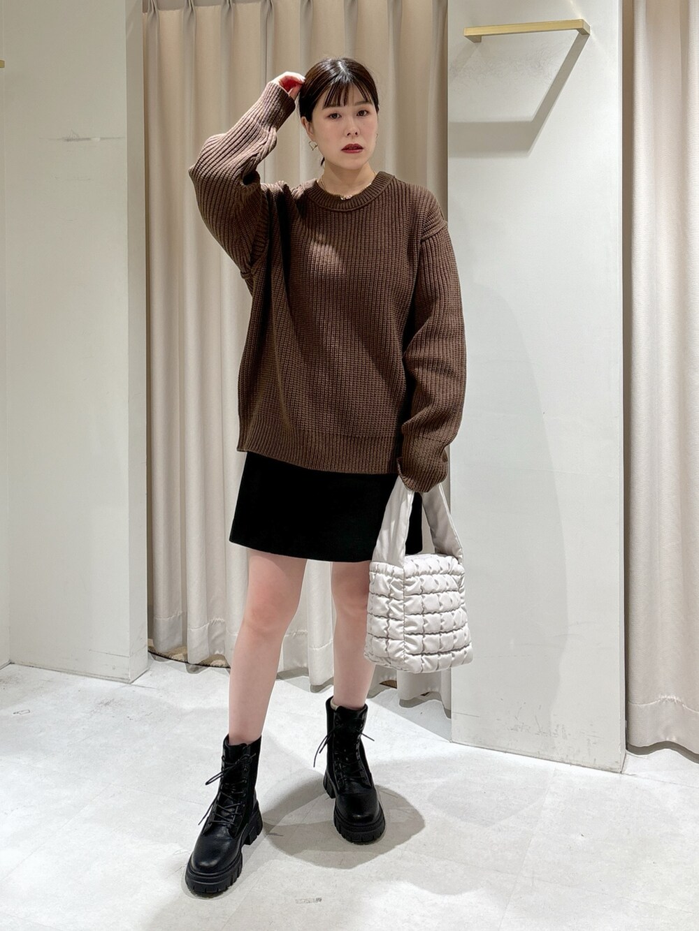 ブラウン系のニット/セーター、ホワイト系のハンドバッグ、ブラック系のスカートを着用したレディースの秋コーディネートの7枚目の写真