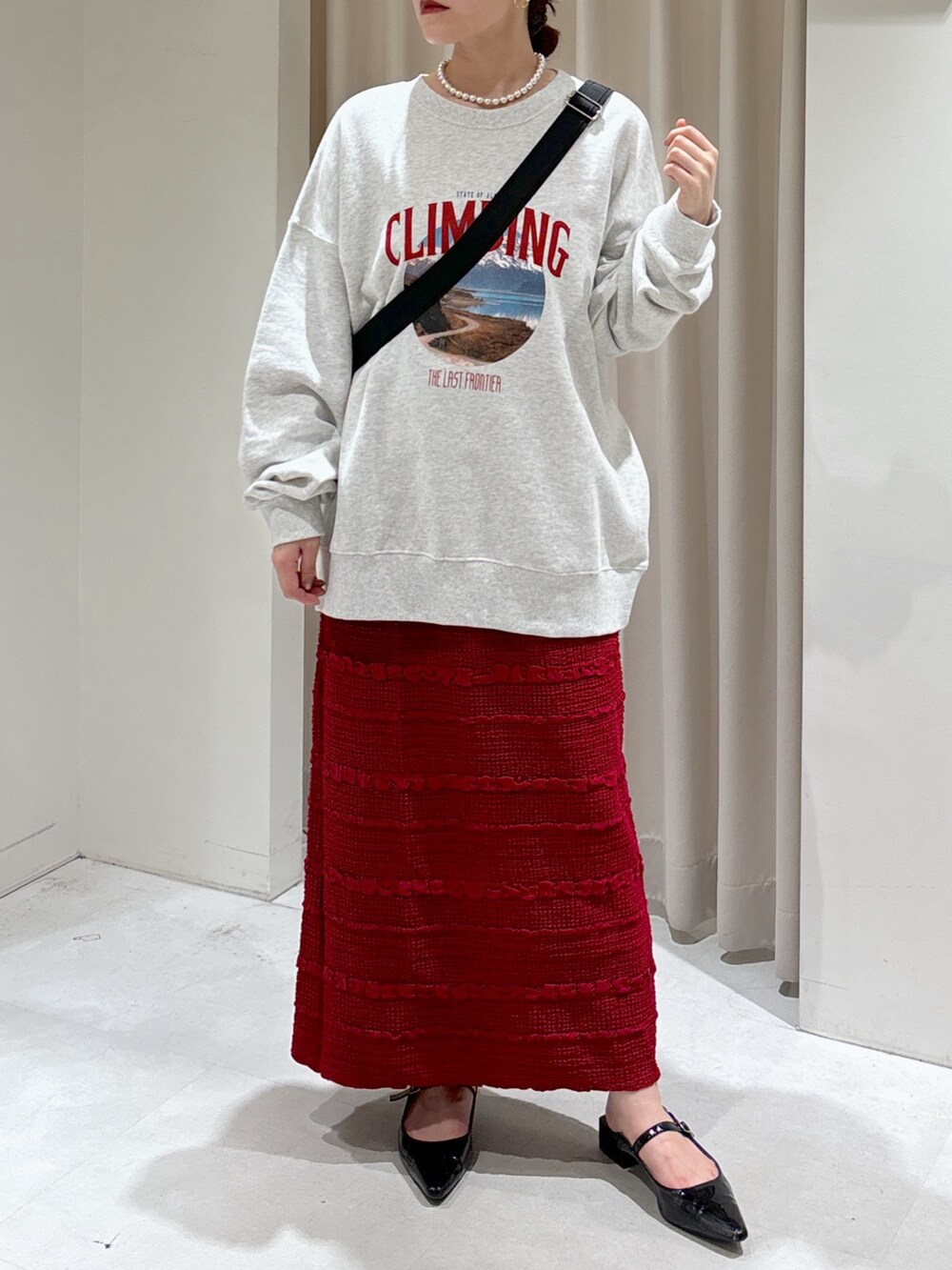 ホワイト系のスウェット、レッド系のスカート、ブラック系のパンプスを着用したレディースの秋コーディネートの2枚目の写真