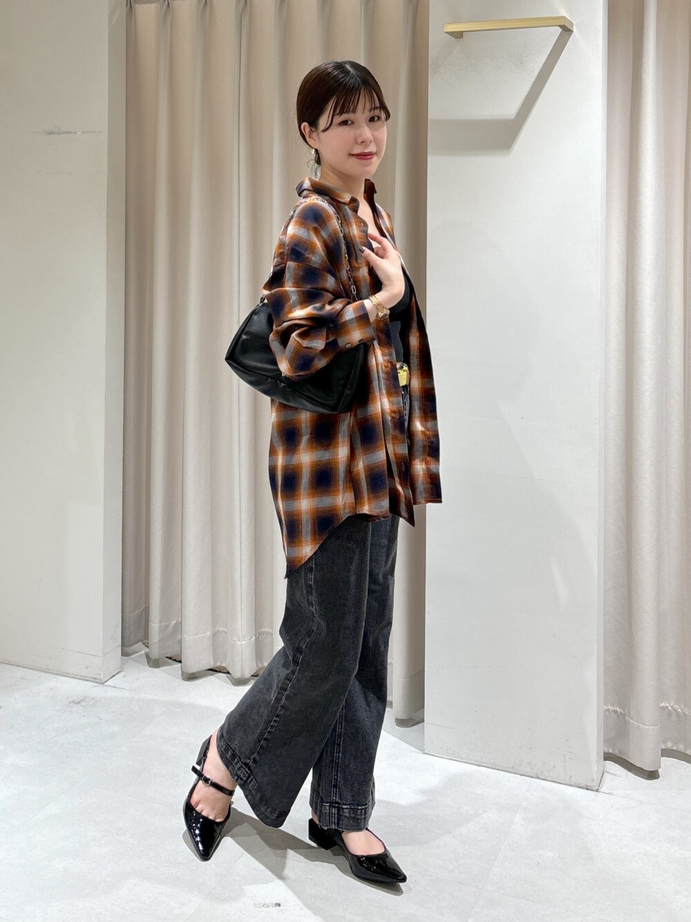 オレンジ系のシャツ/ブラウス、ブラック系のキャミソール、ブラック系のデニムパンツを着用したレディースの秋コーディネートの5枚目の写真