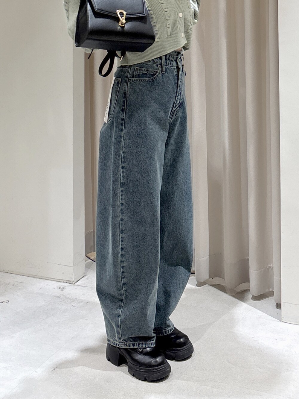 グリーン系のワンピース、ブルー系のデニムパンツ、ブラック系のトートバッグを着用したレディースの冬コーディネートの7枚目の写真