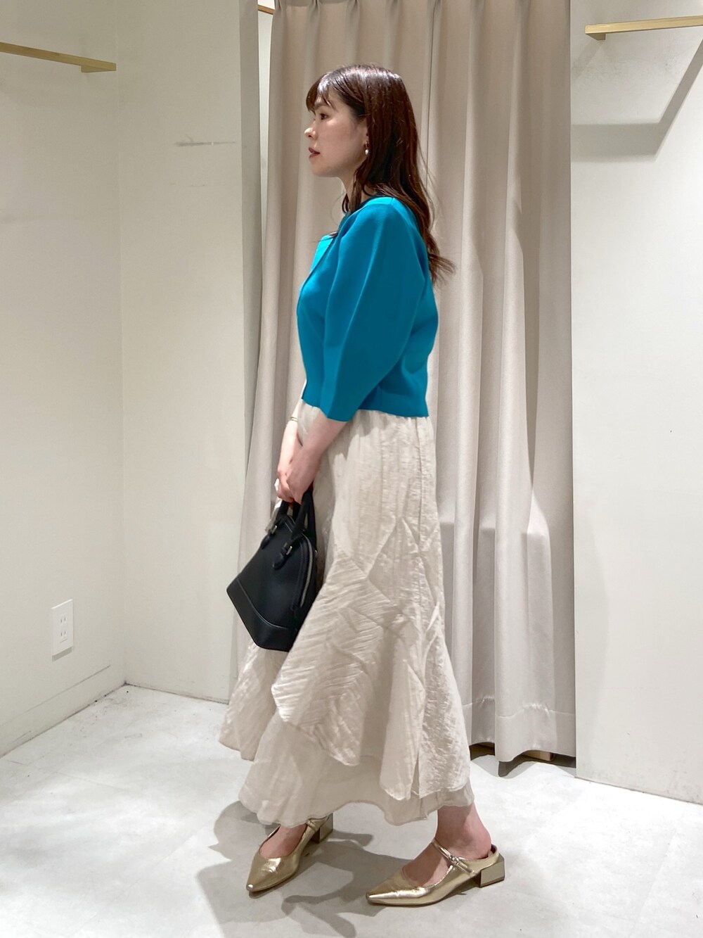 ブルー系のニット/セーター、ホワイト系のスカート、ブラック系のショルダーバッグを着用したレディースの冬コーディネートの5枚目の写真