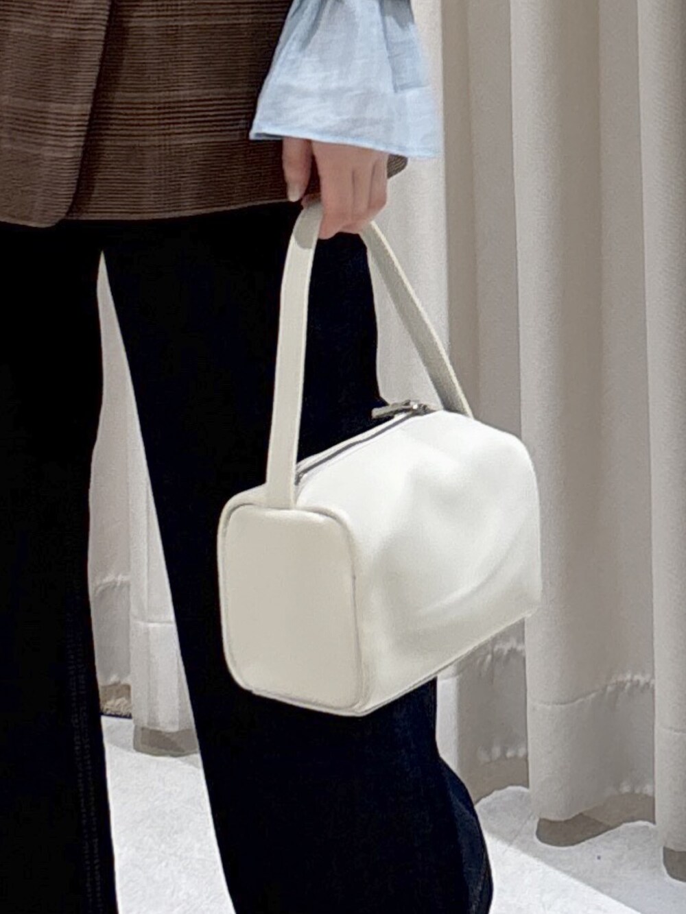 ブラウン系のテーラードジャケット、ホワイト系のハンドバッグ、ブルー系のデニムパンツを着用したレディースの春コーディネートの9枚目の写真