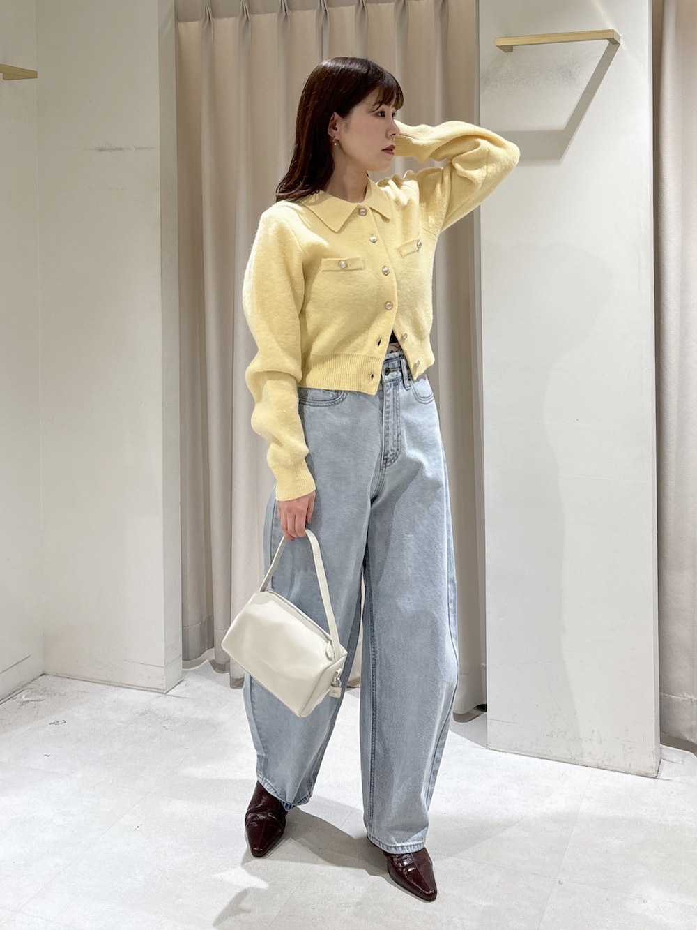 イエロー系のニット/セーター、ブラウン系のパンプス、ブルー系のデニムパンツを着用したレディースの冬コーディネートの7枚目の写真