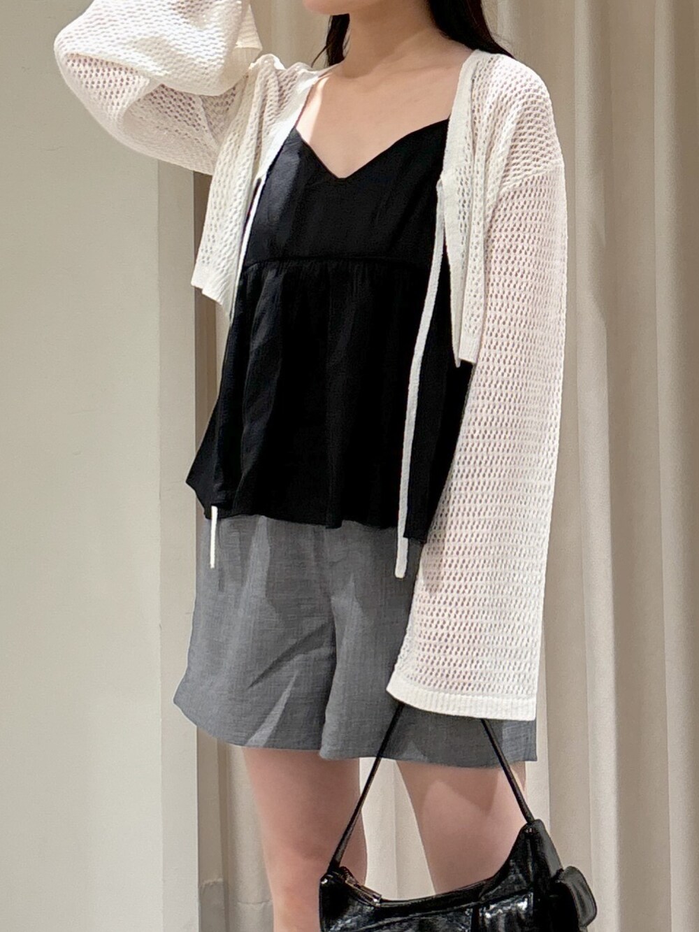 ホワイト系のカーディガン/ボレロ、ブラック系のシャツ/ブラウス、ブラック系のハンドバッグを着用したレディースの夏コーディネートの6枚目の写真