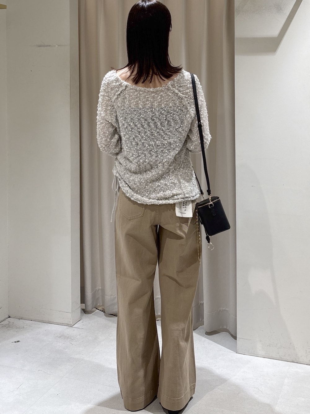 グレー系のニット/セーター、ブラック系のショルダーバッグ、ベージュ系のデニムパンツを着用したレディースの秋コーディネートの3枚目の写真