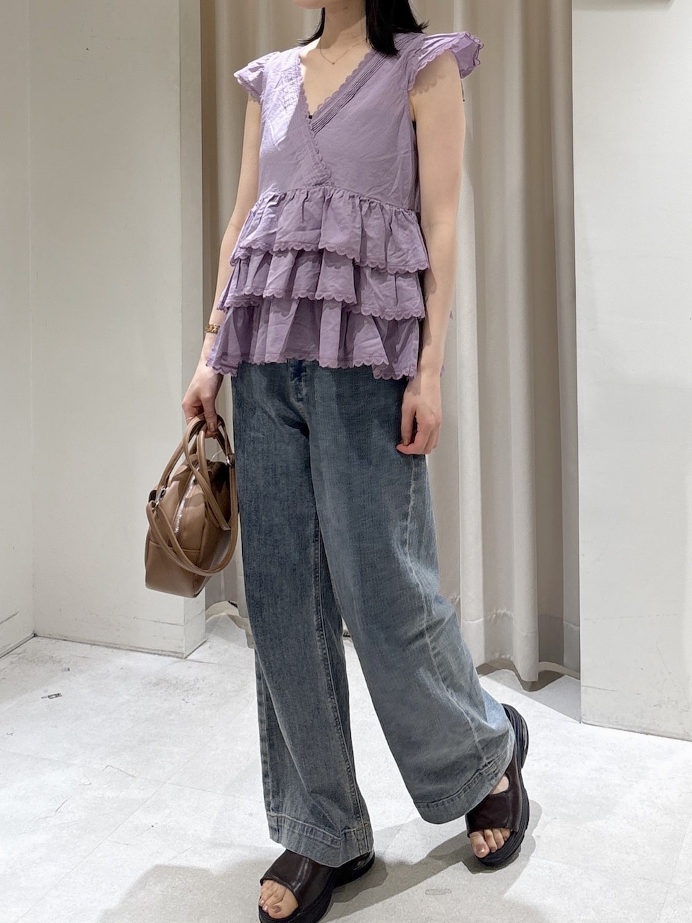 パープル系のシャツ/ブラウス、ブラウン系のハンドバッグ、ブルー系のデニムパンツを着用したレディースの夏コーディネートの2枚目の写真