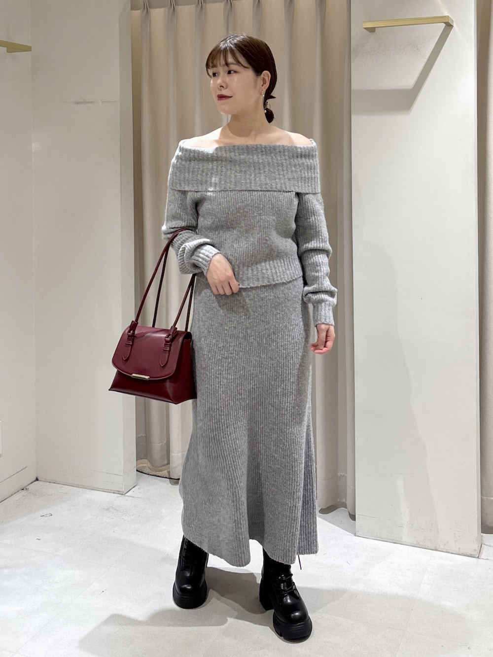 グレー系のワンピース、レッド系のショルダーバッグ、ブラック系のブーツを着用したレディースの秋コーディネートの2枚目の写真