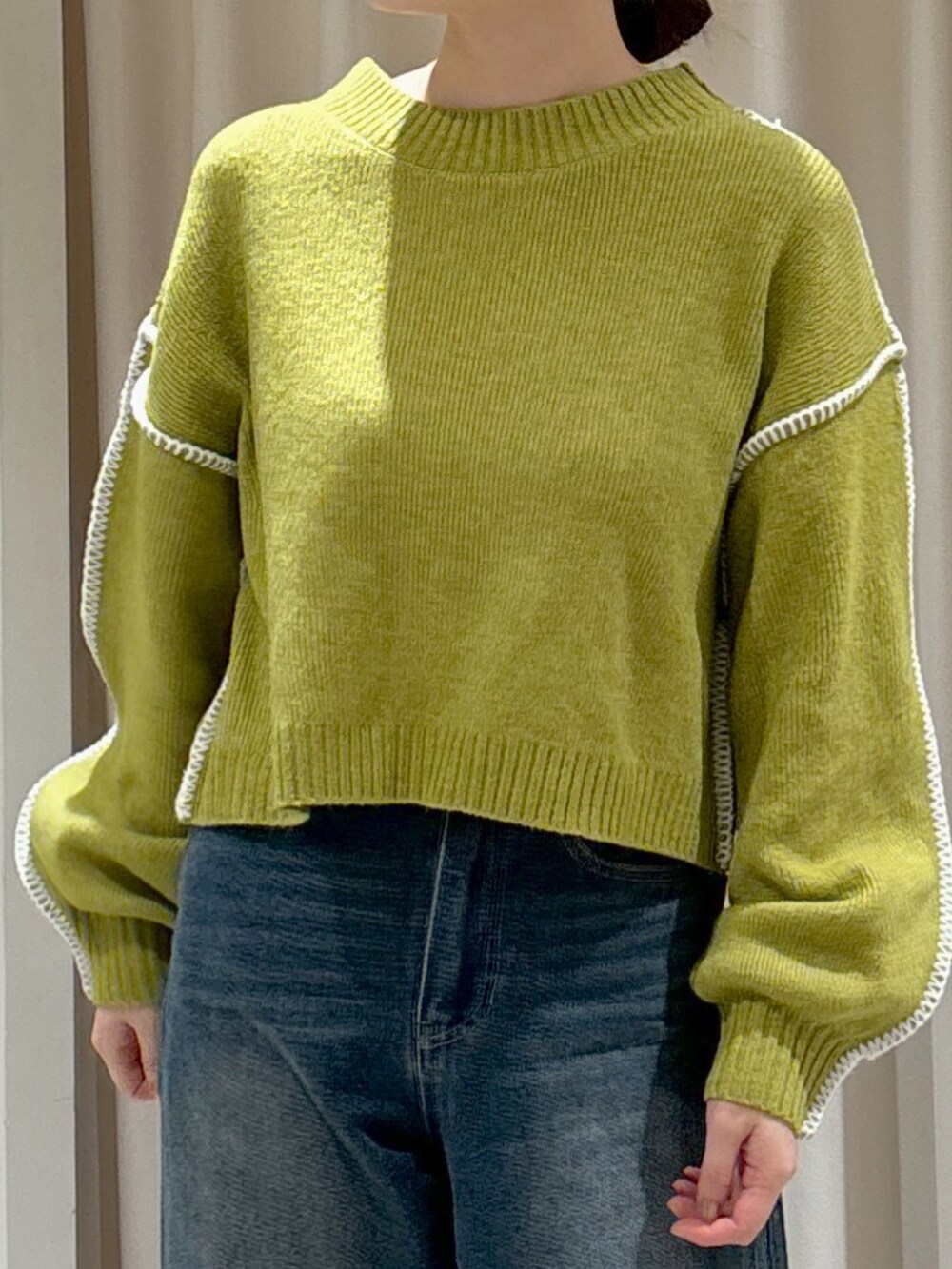 グリーン系のニット/セーター、ブルー系のデニムパンツ、ブラウン系のショルダーバッグを着用したレディースの冬コーディネートの2枚目の写真