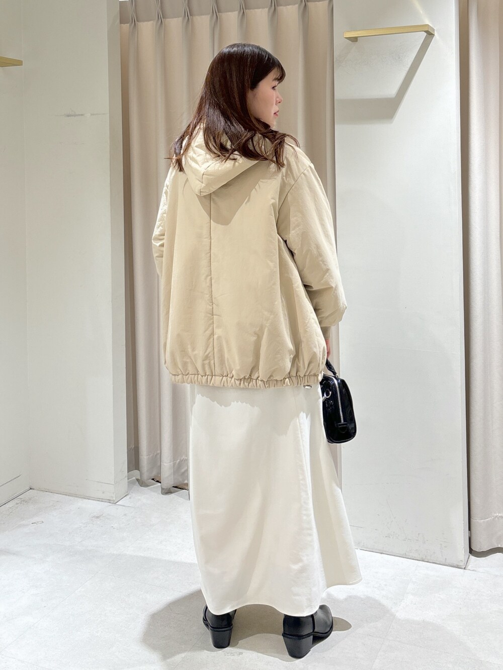 ベージュ系のブルゾン、ブラック系のショルダーバッグ、ホワイト系のスカートを着用したレディースの冬コーディネートの4枚目の写真