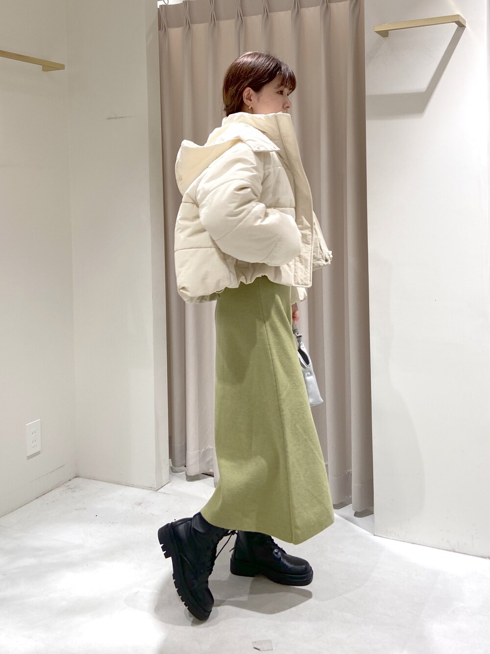 ホワイト系のブルゾン、グリーン系のワンピース、シルバー系のショルダーバッグを着用したレディースの秋コーディネートの2枚目の写真
