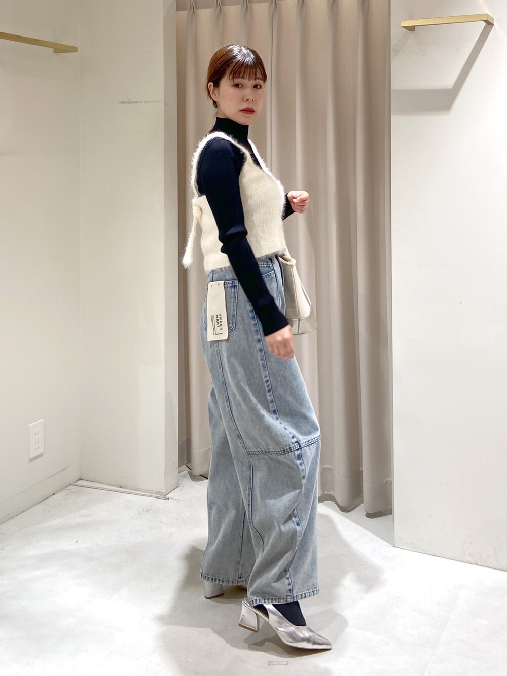 ホワイト系のベスト、ブラック系のニット/セーター、ブルー系のデニムパンツを着用したレディースの冬コーディネートの5枚目の写真