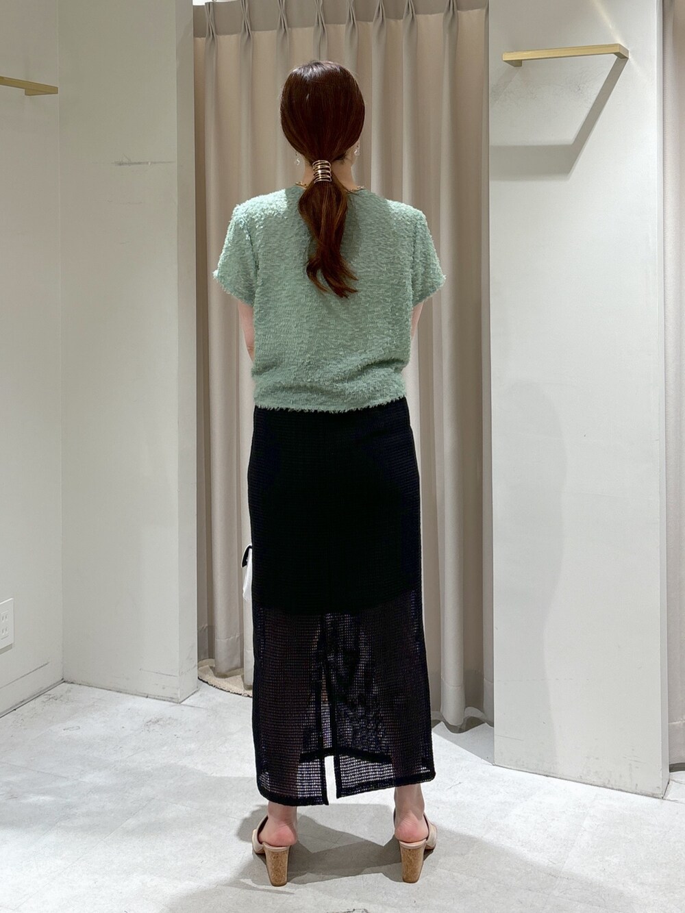 ブラック系のスカート、グレー系のサンダル、ホワイト系のハンドバッグを着用したレディースの夏コーディネートの2枚目の写真