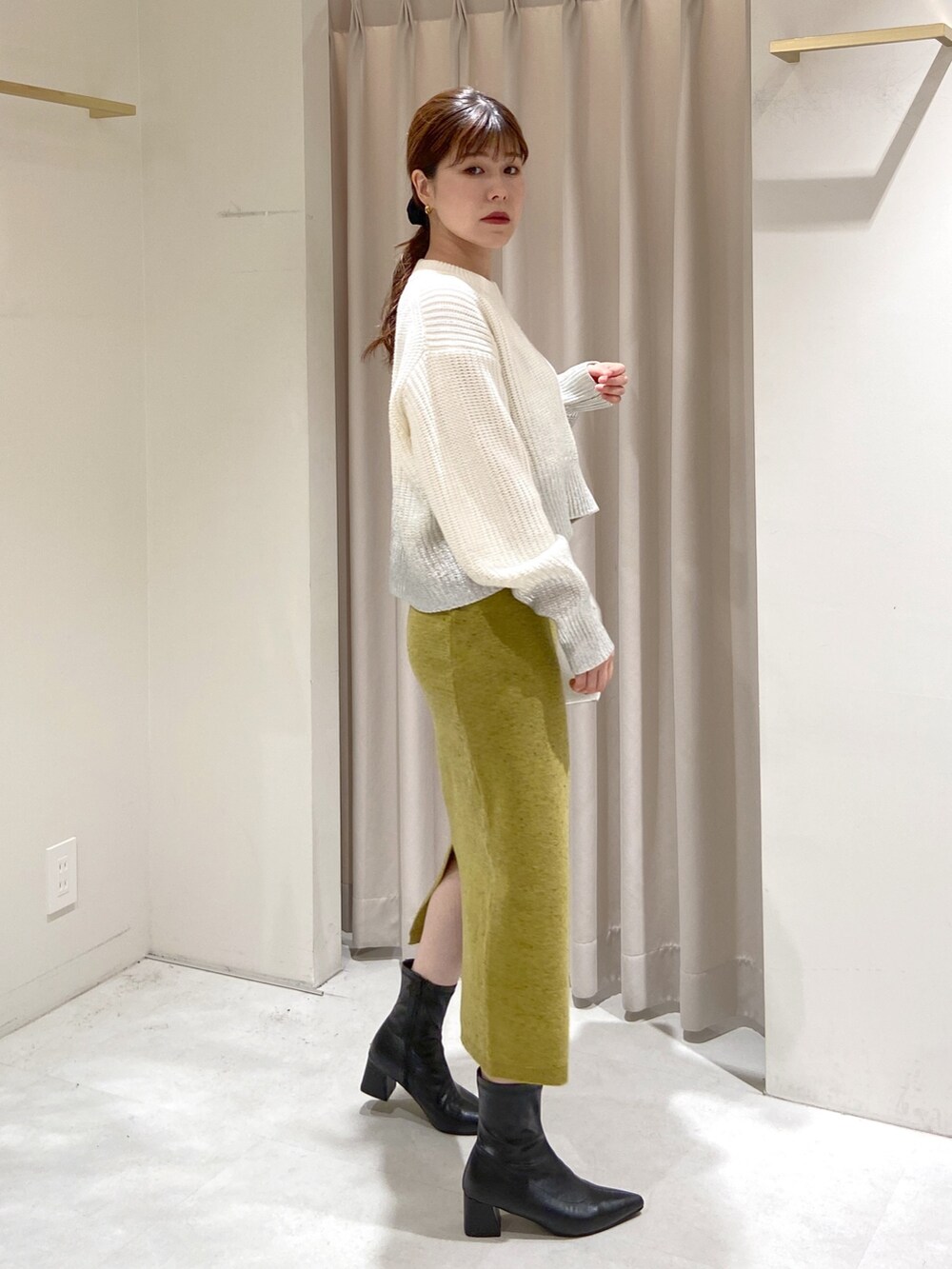 ホワイト系のニット/セーター、グリーン系のスカート、ホワイト系のショルダーバッグを着用したレディースの冬コーディネートの3枚目の写真