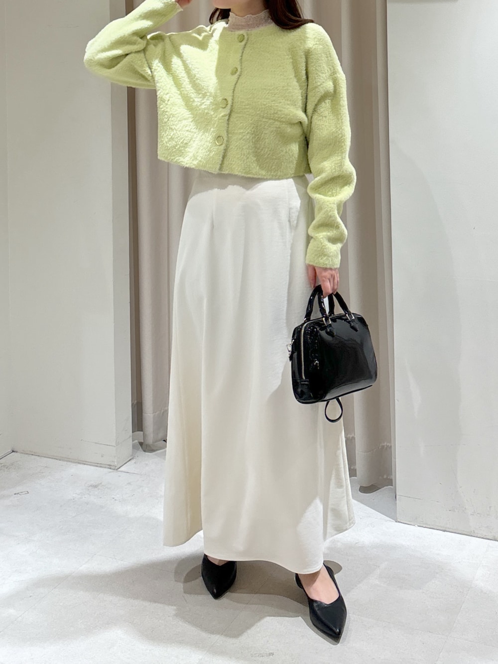 グリーン系のカーディガン/ボレロ、ホワイト系のTシャツ/カットソー、ホワイト系のスカートを着用したレディースの冬コーディネートの2枚目の写真