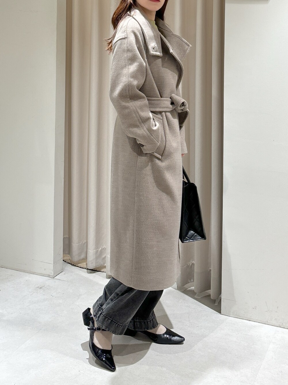 ブラウン系のステンカラーコート、ブラック系のショルダーバッグ、ブラック系のパンプスを着用したレディースの秋コーディネートの4枚目の写真