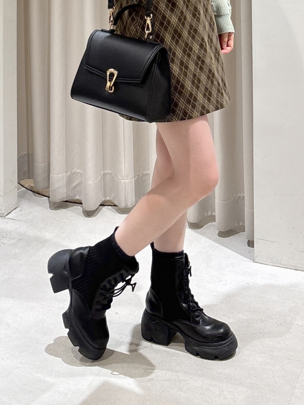 グリーン系のワンピース、ブラウン系のスカート、ブラック系のトートバッグを着用したレディースの冬コーディネートの6枚目の写真